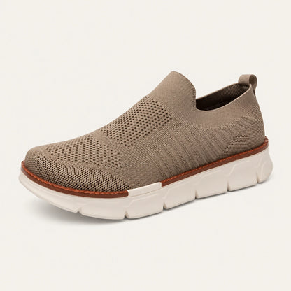 Taupe XE5813 knit slip-on shoe with a brown welt and cream segmented sole on a warm off-white background.