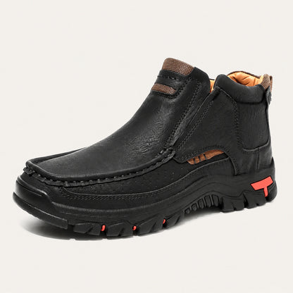 Black 33238 moc-toe slip-on ankle boot with red heel accents on a warm off-white background.