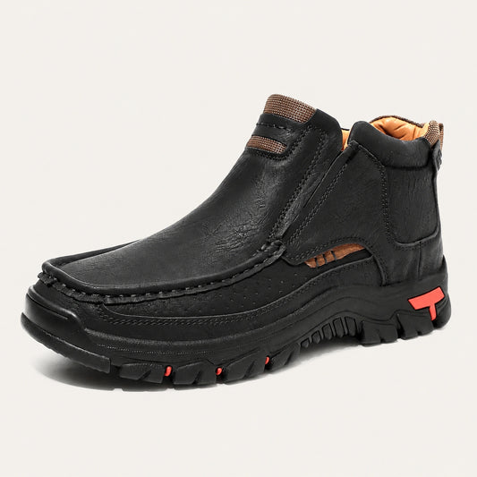 Black 33238 moc-toe slip-on ankle boot with red heel accents on a warm off-white background.